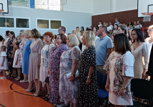 Zebrani nauczyciele i rodzice podczas śpiewania hymnu