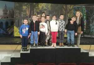 Grupa dzieci z nauczycielem na scenie teatralnej