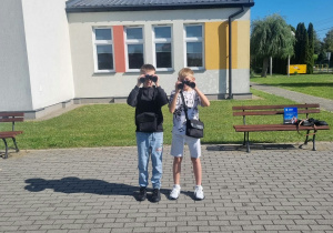 Uczniowie obserwujący przyrodę przez lornetkę