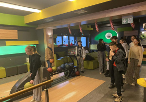 Grupa uczniów przy stanowisku do gry w kręgle